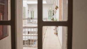 A corridor with a balcony, potted plants, and a railing. - La Galeria de San Antonio (Cádiz)