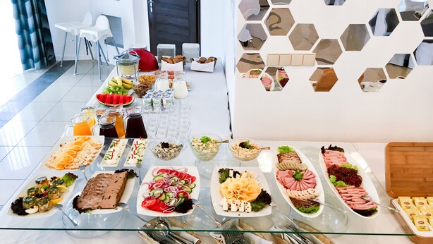 A buffet table with various food items and utensils. - Hotel Kardamon (Tarnow)