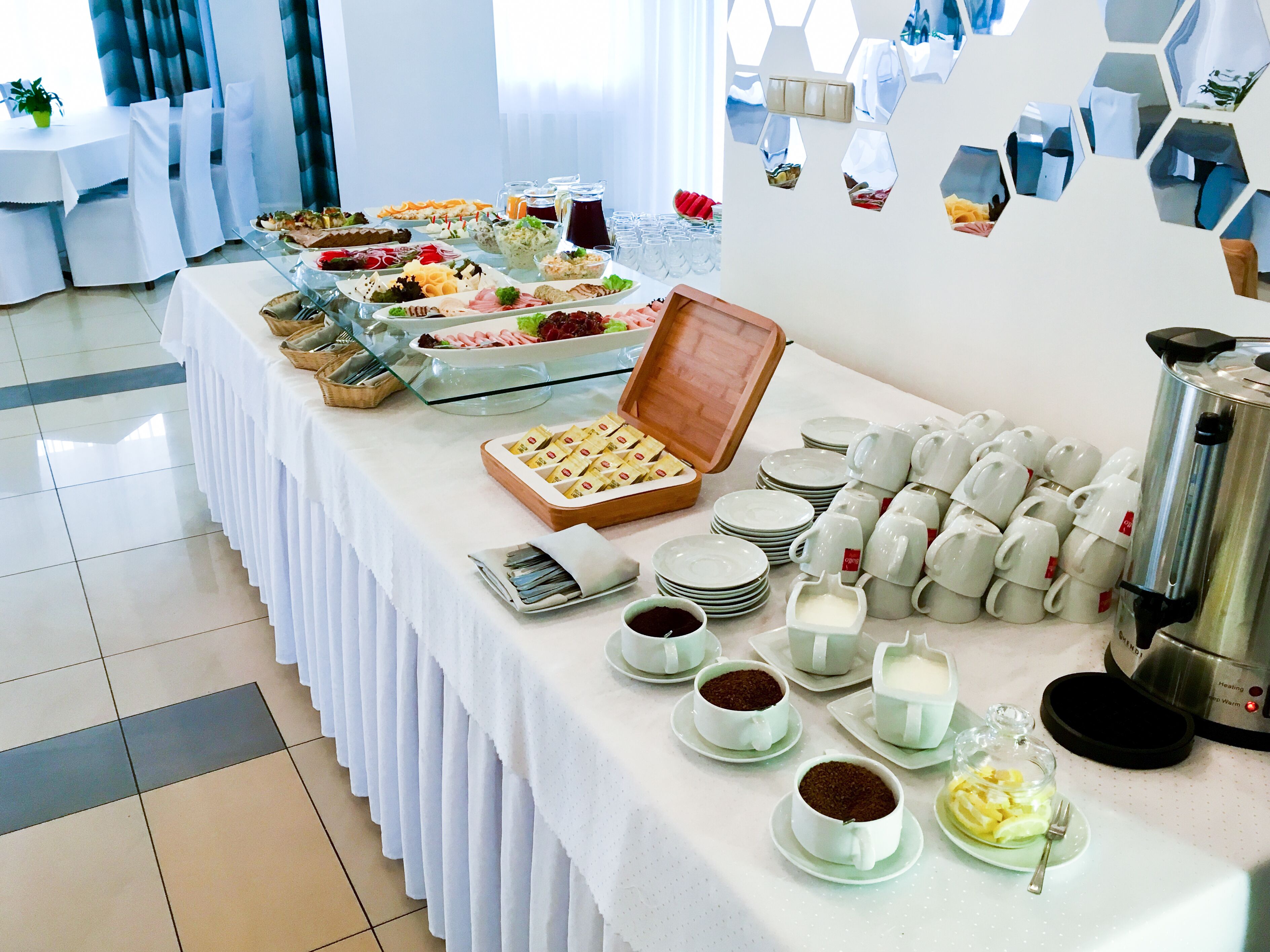 A buffet table with various food items, coffee and tea service, and a coffee maker.