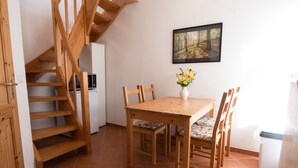 A wooden staircase leading to a second floor, a dining area with a wooden table and chairs, a white refrigerator, and a framed picture on the wall. - Experience with us the Harz im Glück! Vacation for two in Wernigerode! (Wernigerode)