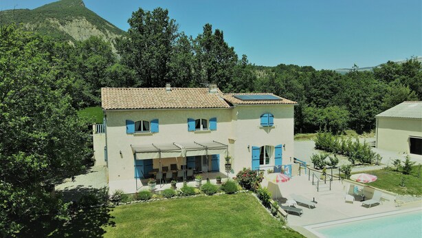 Un bâtiment à deux étages, doté d’un toit en tuiles, d’un patio couvert avec des meubles d’extérieur et d’une piscine.