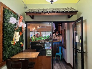 A cozy cafe interior with a green wall, wooden furniture, and a 'Breeze Coffee' sign.