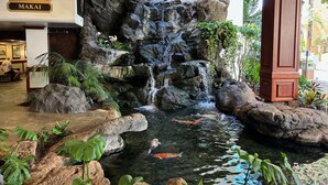 A hotel lobby with a rock waterfall and koi pond.
