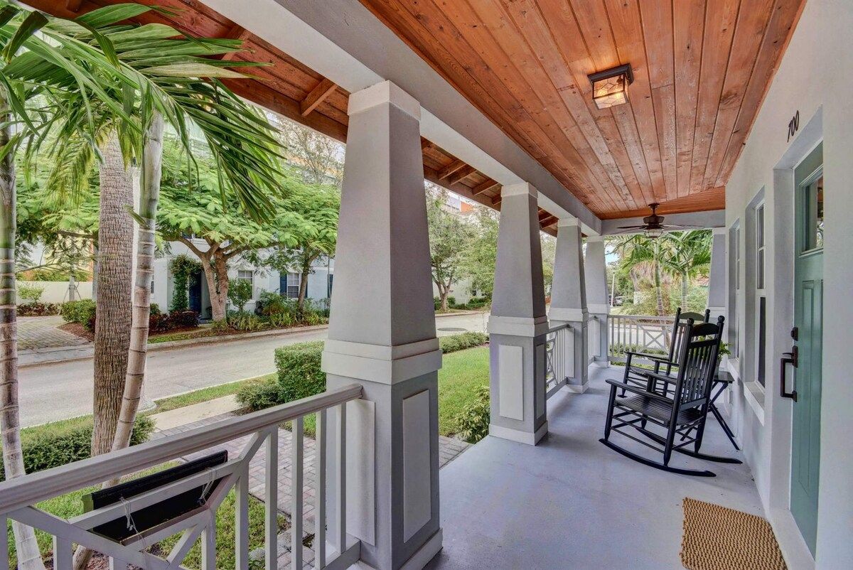 A covered porch with a wooden ceiling, white columns, and a rocking chair.