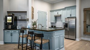 Una cucina con mobili blu, un frigorifero in acciaio inossidabile e una macchina per caffè.