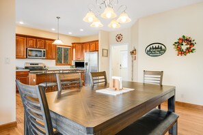 Une cuisine moderne avec des meubles en bois, un îlot central et un coin repas comprenant une grande table et des chaises en bois.