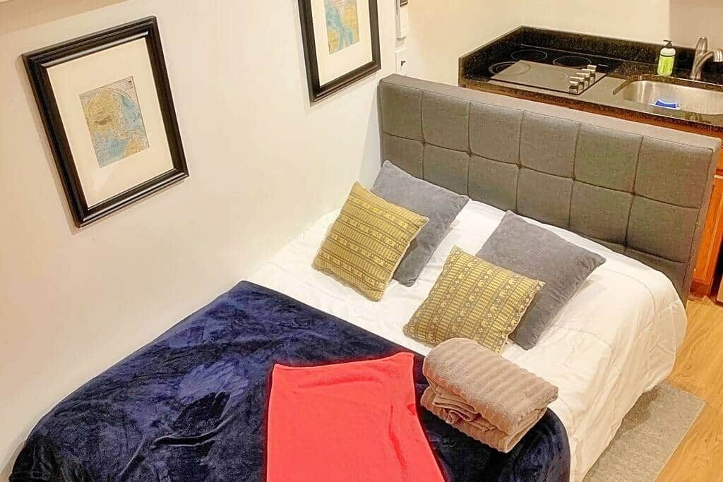 A bed with a grey headboard, a blue blanket, and multiple pillows.