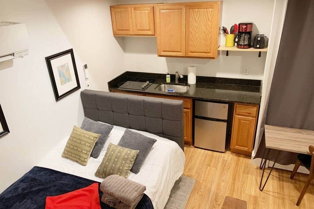 Een kleine kamer met een bed, een kitchenette en een eethoekje.