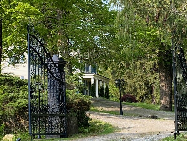 Ein verschlossener Eingang mit schmiedeeisernem Tor, das zu einem Gebäude mit Säulen und einer Veranda führt.