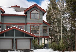 Une maison à deux étages avec un toit rouge et des portes de garage blanches.