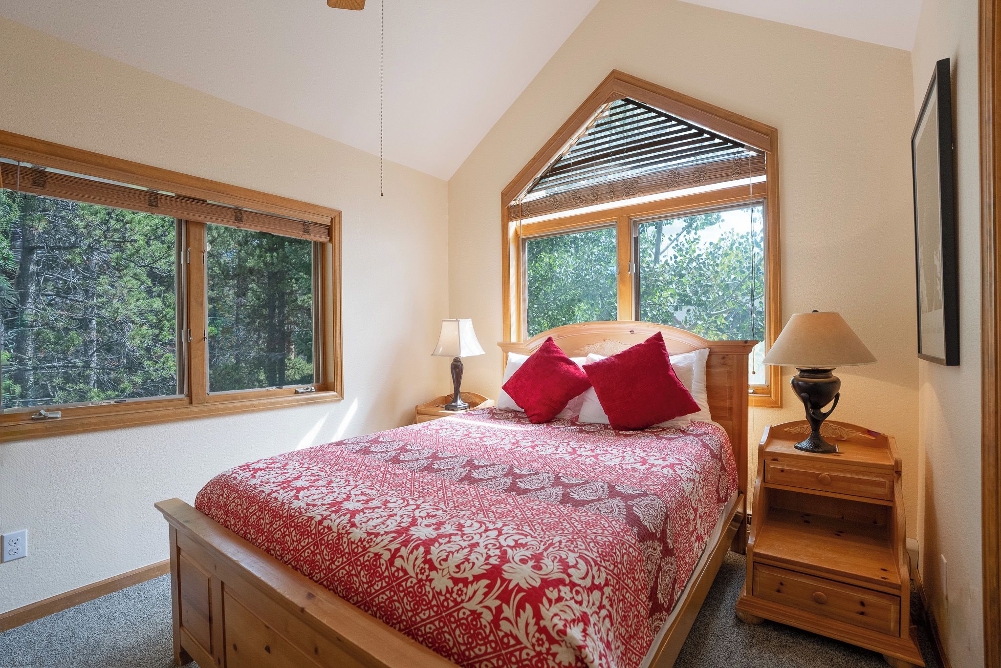 Ein Schlafzimmer mit einem Bett, zwei Nachttischen und großen Fenstern.