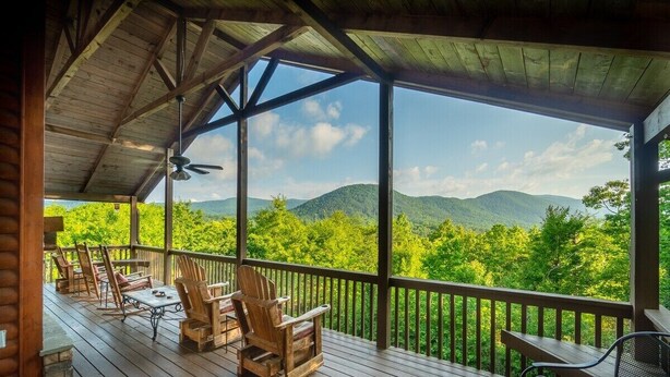 A wooden deck with outdoor furniture, a ceiling fan, and a view of green mountains. - 4BR cabin with hot tub, game room, fire pit, and mountain views. (Sautee Nacoochee)