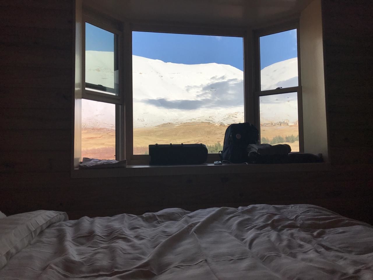 A room with a bed and a window overlooking a snowy landscape.