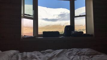 A room with a bed and a window overlooking a snowy landscape.