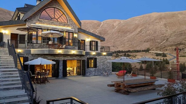 A multi-story house with a large balcony, outdoor seating area, and a staircase leading to the upper levels. - Chalet de Charme (Al Arz)