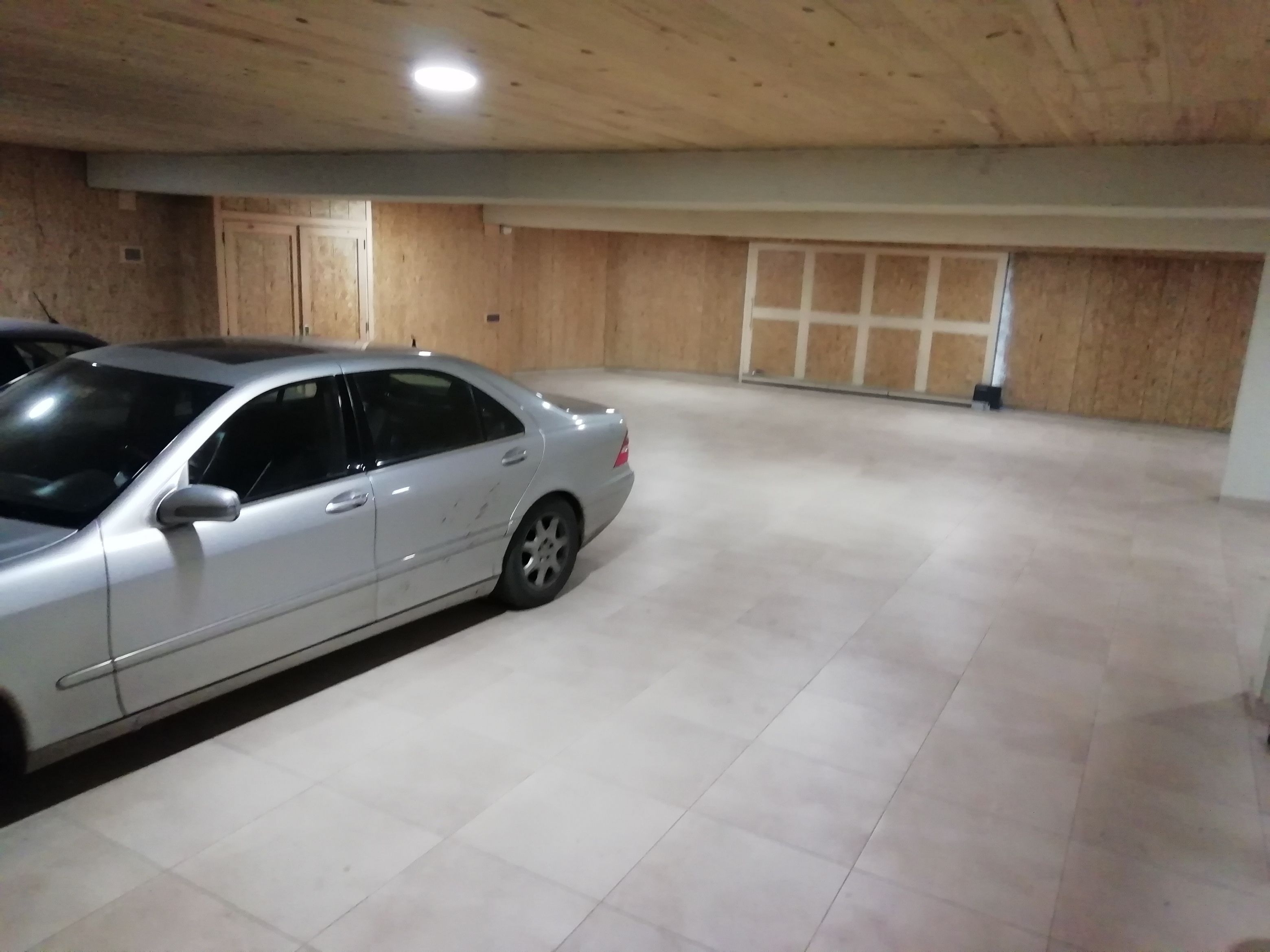Een ruime parkeergarage, met een zilvergrijze auto op de voorgrond.