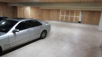 Een ruime parkeergarage, met een zilvergrijze auto op de voorgrond.