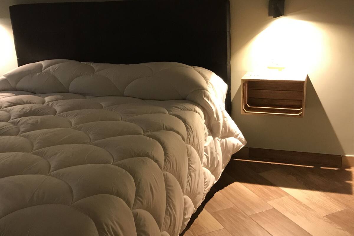 Un lit avec une tête de lit sombre et une table de chevet avec une lampe.