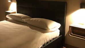 A bed with a dark headboard, two pillows, and a bedside lamp on a wooden nightstand. - Terrazza Carlo terzo (Naples)