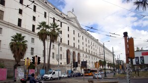 A cobblestone street with a historic building, palm trees, and a tram. - Terrazza Carlo terzo (Naples)