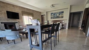 A spacious living area with a fireplace, a dining table with chairs, and a large painting on the wall. - El Carmelo Mountain Lodge (Potrerillos)
