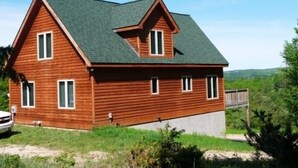 Une maison en bois à deux étages, dotée d’un toit à pignon très incliné et d’un petit porche.