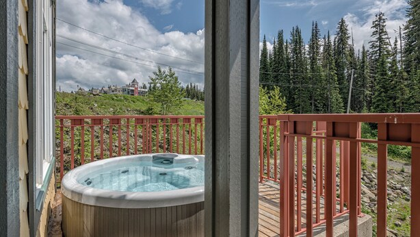 A hot tub on a wooden deck with a red railing, overlooking a forested hillside. - Bright, upgraded townhouse in Creekside w/laundry, hot tub, close to village (Silver Star Mountain)