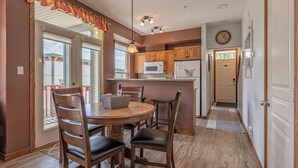A kitchen with wooden cabinets, a microwave, and a refrigerator. There is a dining table with chairs and a basket. - Bright, upgraded townhouse in Creekside w/laundry, hot tub, close to village (Silver Star Mountain)
