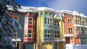 Une rangée de maisons colorées de style victorien, recouvertes de neige.