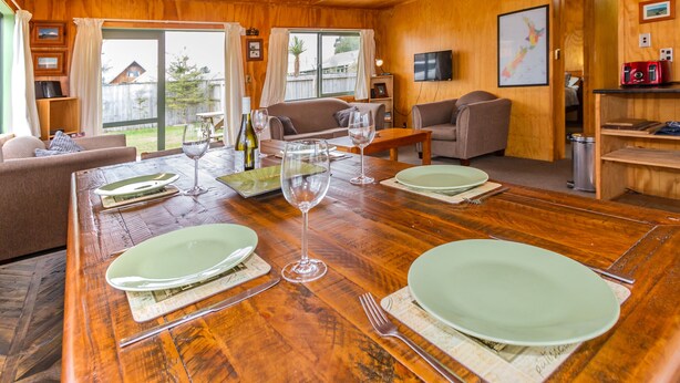 L’intérieur est en bois et comprend une table à manger pour quatre personnes, un canapé et un téléviseur fixé au mur.