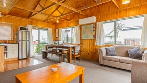 Une chaleureuse cabane en bois comprenant un coin repas, une cuisine et un salon avec un canapé et une table.