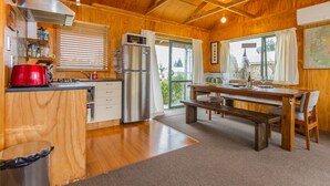 L’intérieur d’un chalet en bois comprend une cuisine, un coin repas et une grande fenêtre.