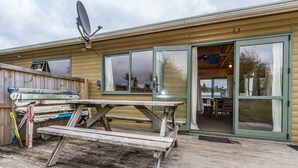 Une terrasse en bois avec une table de pique-nique et des paires de skis appuyés contre une clôture.
