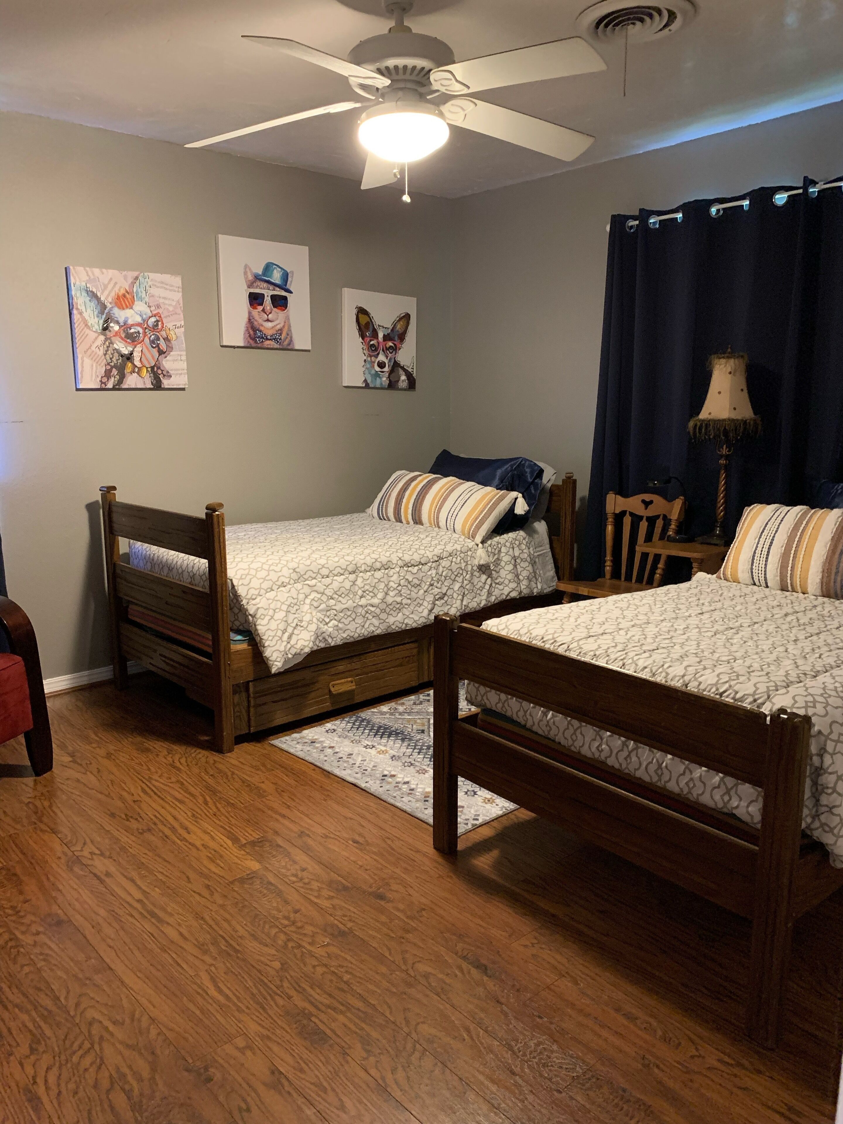 A bedroom with two wooden beds, a ceiling fan, and artwork on the wall.