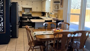 Una cocina con comedor, que incluye una araña, armarios blancos y un letrero que dice 'WELCOME'.