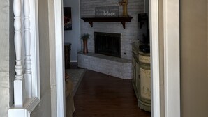 Un pasillo que conduce a una sala de estar con chimenea, una estatua y un letrero motivacional.