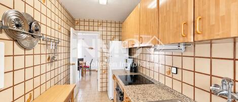 Una cocina con armarios de madera, encimera de granito, un lavamanos y un comedor visible al fondo.