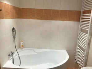 Ein Badezimmer mit einer weißen Badewanne, einer Duschbrause und einem weißen Handtuchhalter.