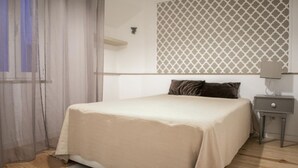 Un dormitorio con cama, mesita de noche, lámpara y pared con diseño.