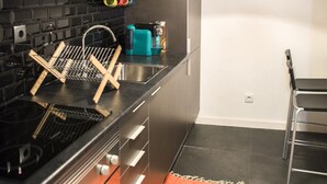 Una cocina moderna con electrodomésticos de acero inoxidable, un microondas y un reloj en la pared.