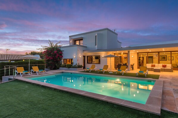 A modern house with a swimming pool, outdoor seating, and a well-maintained garden.