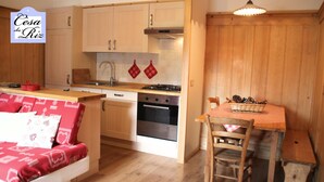 A cozy kitchen with wooden cabinets, a stove, and a dining area with a table and chairs.