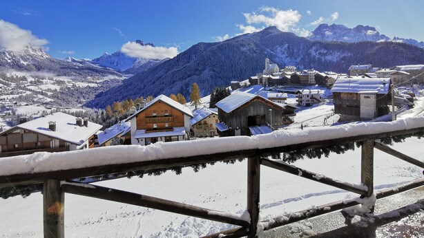 A snow-covered village with wooden houses and a mountain backdrop.