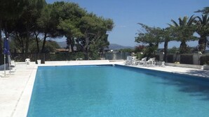 A rectangular swimming pool with clear blue water, surrounded by a white deck and lounge chairs.
