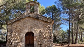 Una capilla de piedra con una puerta de madera y escalones que conducen a ella, rodeada de árboles.