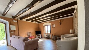 Amplia sala de estar con un sofá a rayas, un sillón blanco y una zona de comedor con mesa y sillas.