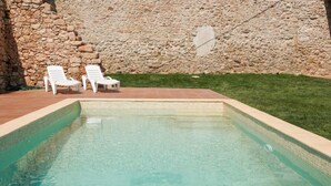 A swimming pool with two white lounge chairs and a stone wall in the background. - XIII century cottage surrounded of vineyards  (Aiguamúrcia)