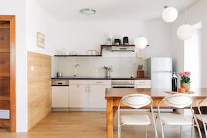 A modern kitchen with white cabinets, a wooden countertop, and a dining area with metal chairs.