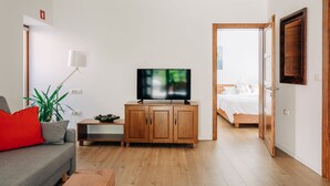 Una sala de estar moderna con televisor, mueble de madera y sofá.