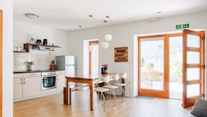 Una cocina moderna con armarios blancos, una mesa de comedor de madera y vistas al exterior.